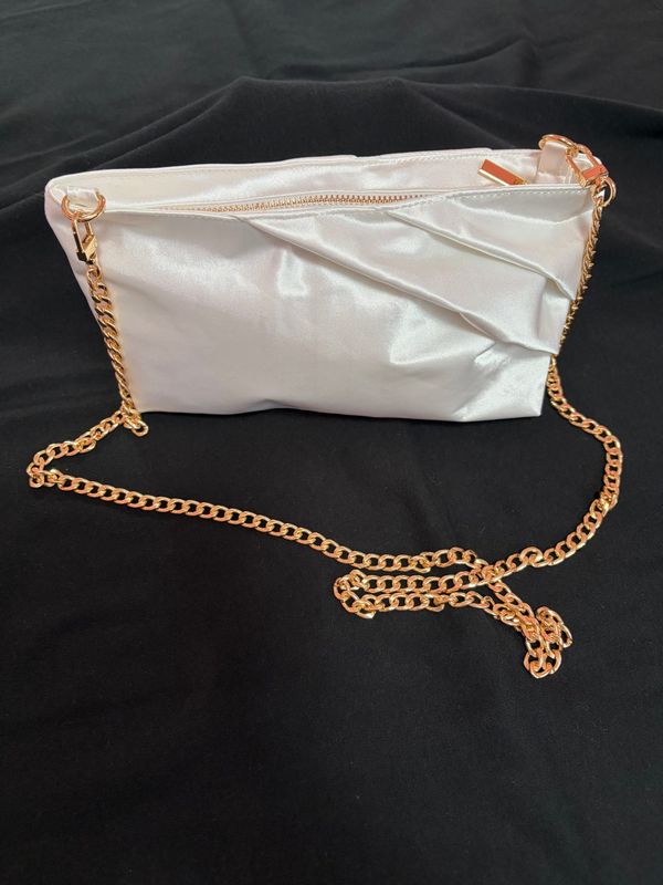 A white satin clutch bag with a gold chain strap