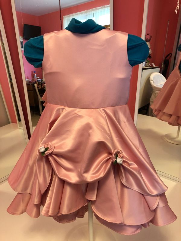 A pink satin child’s dress with gathered rosette pick-ups on a dress form