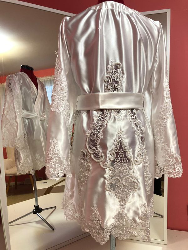 The back of an heirloom satin robe with a cascade of lace appliqué, on a dress form